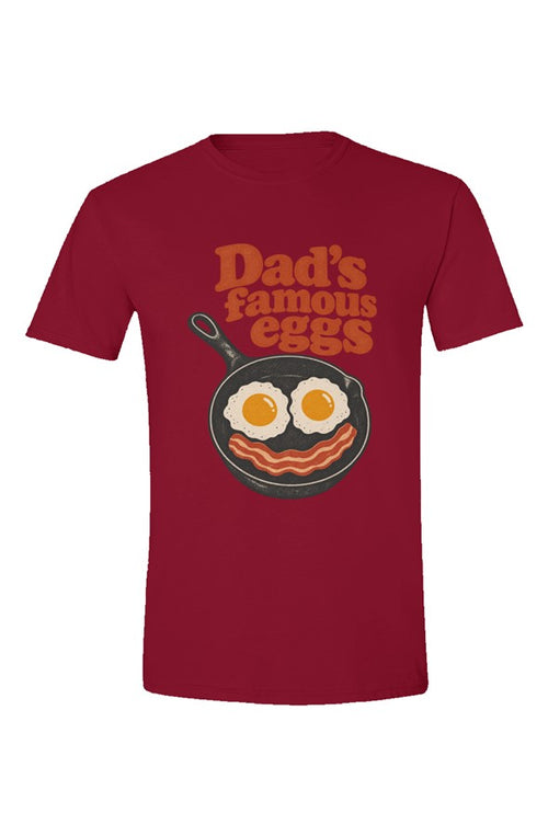Cardinal Red t-shirt with Dad's famous eggs lettering over a skillet with eggs and bacon, flat front view on white.